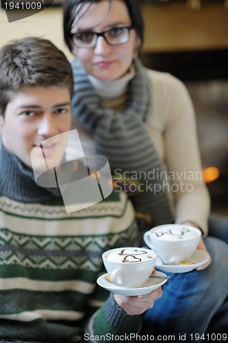 Image of Young romantic couple sitting and relaxing in front of fireplace