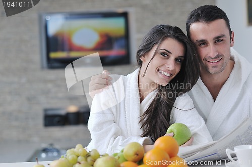 Image of Happy couple reading the newspaper in the kitchen at breakfast