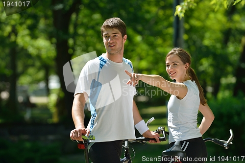 Image of Happy couple riding bicycle outdoors
