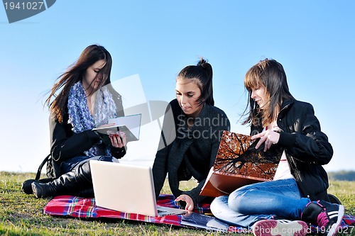 Image of group of teens working on laptop outdoor