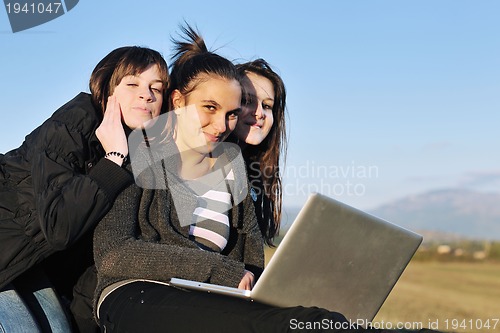 Image of group of teens working on laptop outdoor