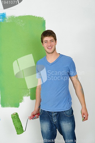 Image of handsome young man paint white wall in color