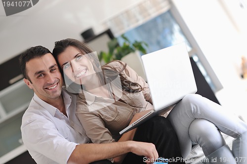 Image of joyful couple relax and work on laptop computer at modern home