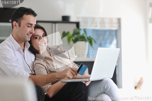Image of joyful couple relax and work on laptop computer at modern home