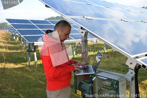 Image of engineer using laptop at solar panels plant field