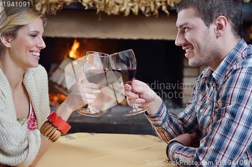 Image of Young romantic couple sitting and relaxing in front of fireplace