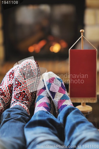 Image of Young romantic couple sitting and relaxing in front of fireplace
