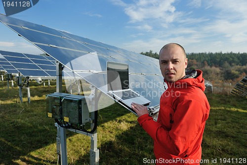 Image of engineer using laptop at solar panels plant field