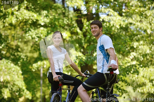Image of Happy couple riding bicycle outdoors