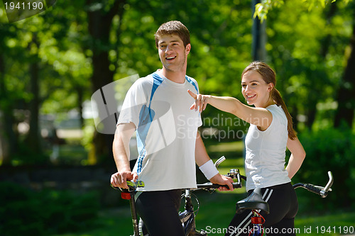 Image of Happy couple riding bicycle outdoors