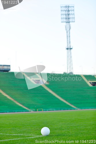 Image of Soccer ball on grass at goal and stadium in background