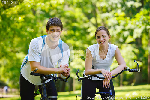 Image of Happy couple riding bicycle outdoors