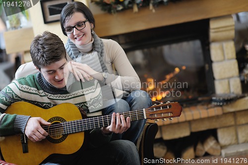 Image of Young romantic couple sitting and relaxing in front of fireplace