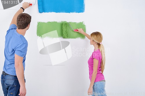 Image of happy couple paint wall at new home