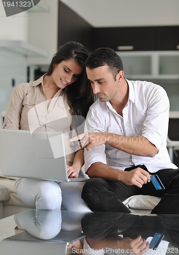 Image of joyful couple relax and work on laptop computer at modern home