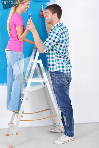 Image of happy couple paint wall at new home