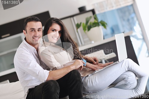 Image of joyful couple relax and work on laptop computer at modern home