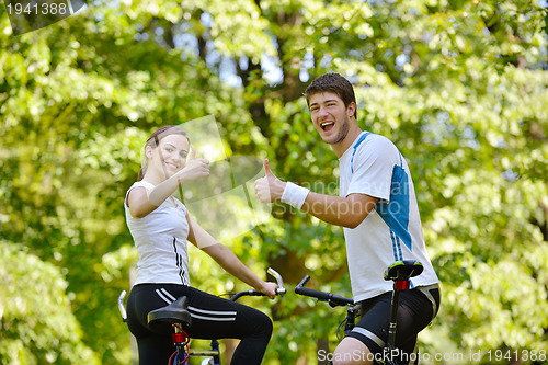Image of Happy couple riding bicycle outdoors