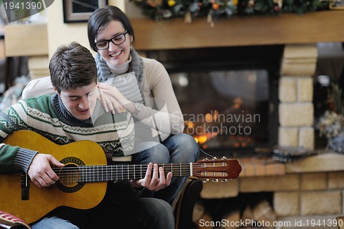 Image of Young romantic couple sitting and relaxing in front of fireplace