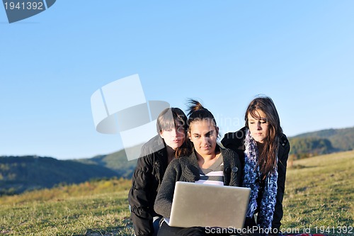 Image of group of teens working on laptop outdoor
