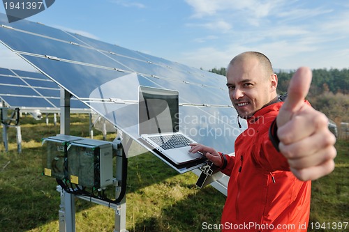 Image of engineer using laptop at solar panels plant field