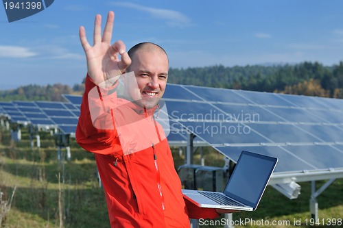 Image of engineer using laptop at solar panels plant field