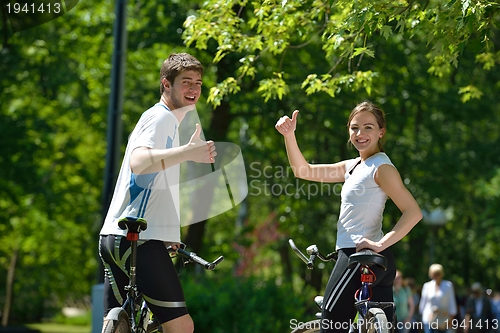Image of Happy couple riding bicycle outdoors