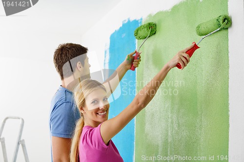 Image of happy couple paint wall at new home