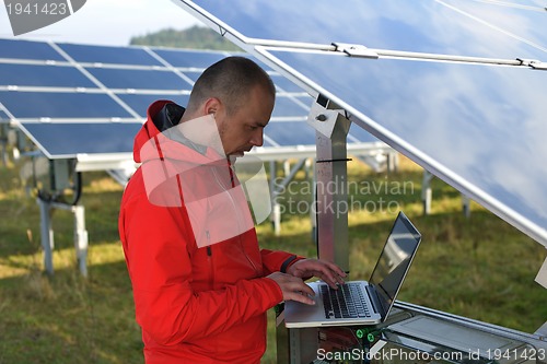 Image of engineer using laptop at solar panels plant field