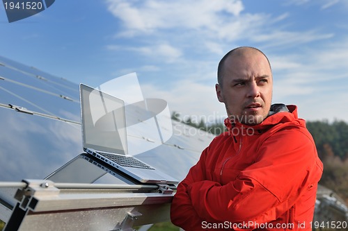 Image of engineer using laptop at solar panels plant field