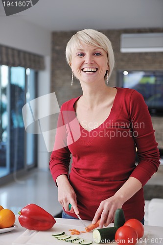 Image of happy  beautiful blonde  woman prepare food in  the kitchen