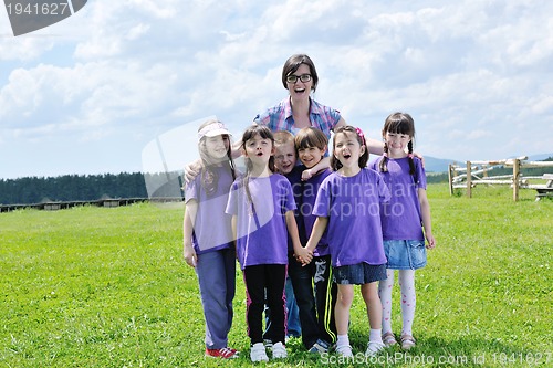 Image of happy kids group with teacher in nature