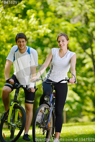 Image of Happy couple riding bicycle outdoors