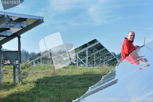 Image of engineer using laptop at solar panels plant field