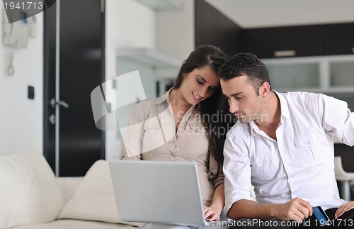 Image of joyful couple relax and work on laptop computer at modern home