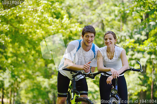 Image of Happy couple riding bicycle outdoors