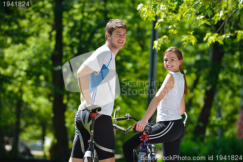 Image of Happy couple riding bicycle outdoors