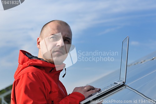 Image of engineer using laptop at solar panels plant field