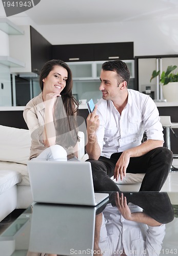 Image of joyful couple relax and work on laptop computer at modern home