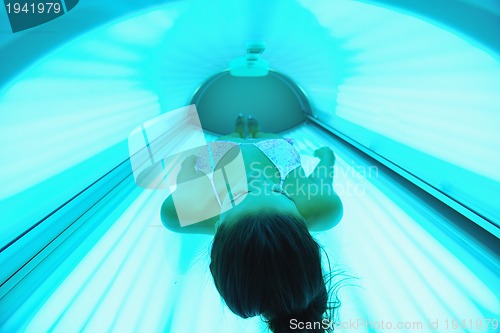 Image of Beautiful young woman tanning in solarium