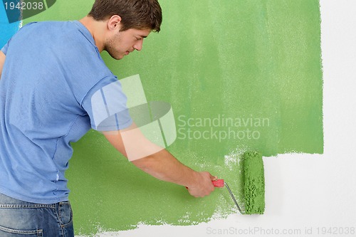 Image of handsome young man paint white wall in color