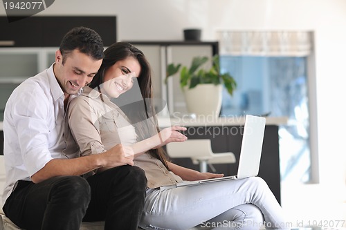 Image of joyful couple relax and work on laptop computer at modern home