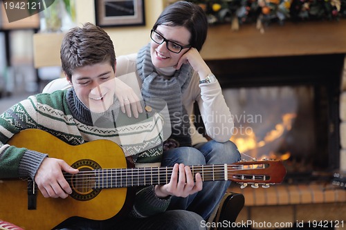 Image of Young romantic couple sitting and relaxing in front of fireplace