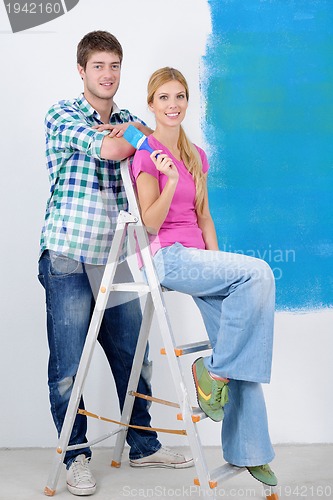 Image of happy couple paint wall at new home