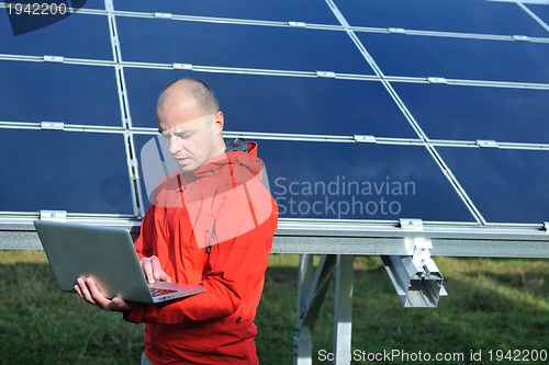 Image of engineer using laptop at solar panels plant field