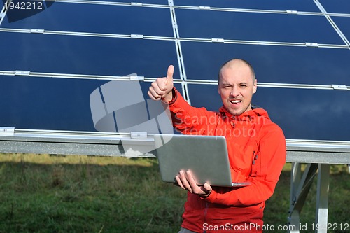 Image of engineer using laptop at solar panels plant field