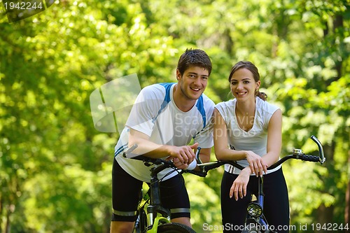 Image of Happy couple riding bicycle outdoors