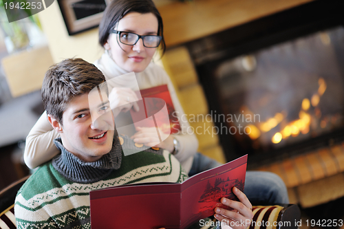 Image of Young romantic couple relax on sofa in front of fireplace at hom