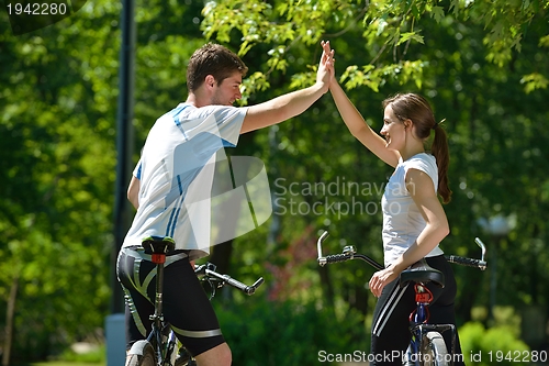 Image of Happy couple riding bicycle outdoors