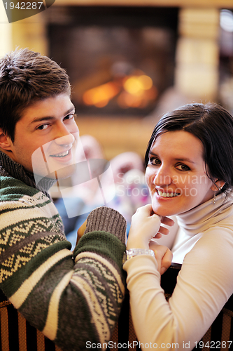 Image of Young romantic couple relax on sofa in front of fireplace at hom